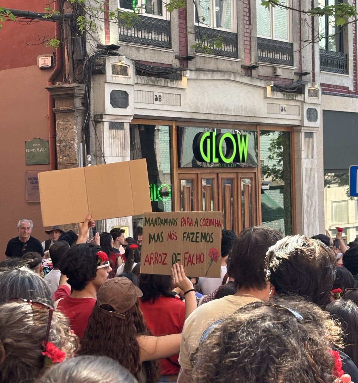 Uma rapariga segura um cartaz na multidão que diz "Mandam-nos para a cozinha, fazemos arroz de facho"